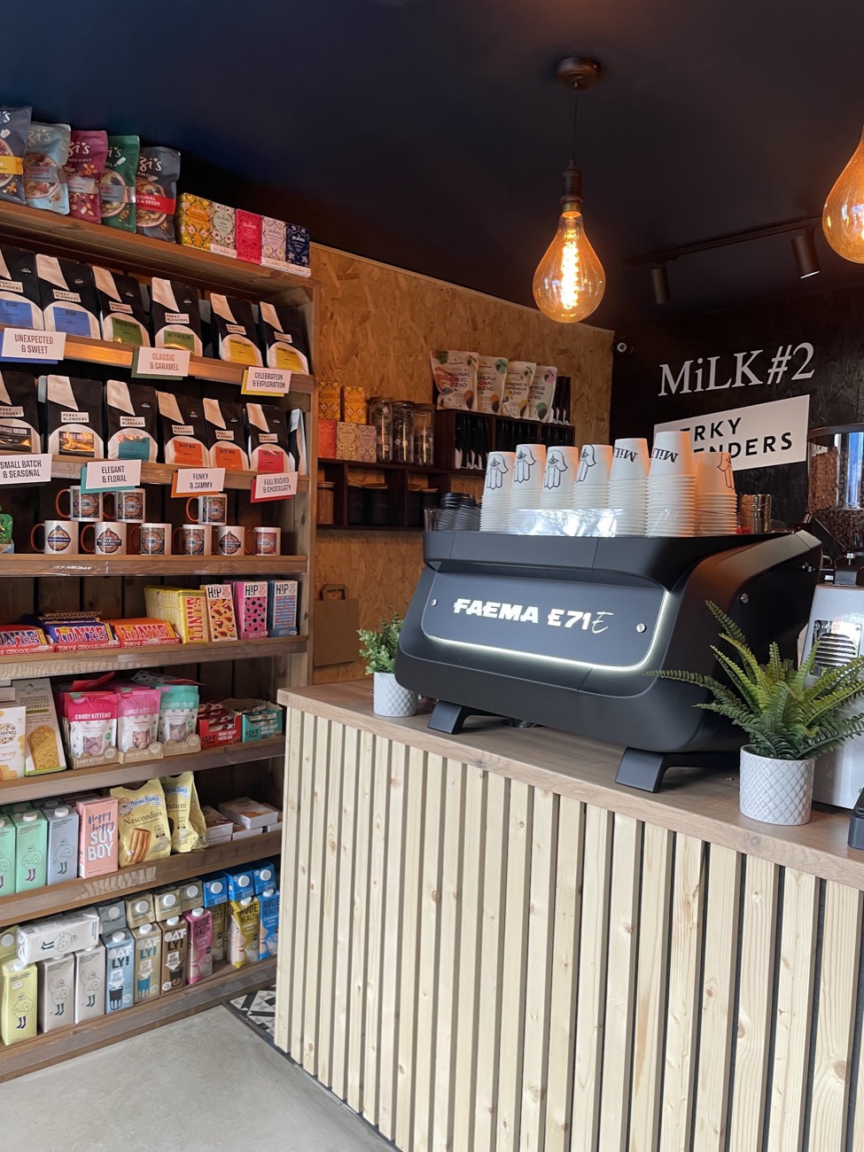 Inside Milk coffee shop in Walthamstow, showing the timber counter, Faema espresso machine and shelves of Perky Blenders coffee